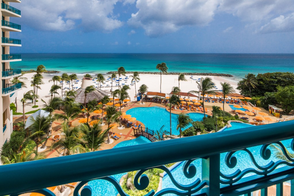 Hilton Barbados Resort, Ocean View, 1 King Bed with Balcony, pools, white sand beach, palm trees, orange umbrellas, orange pool furniture